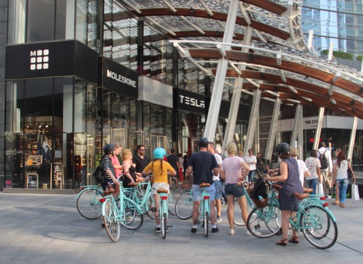 Group of tourists on a bicycle sightseeing tour of Milan in Piazza Gae Aulenti